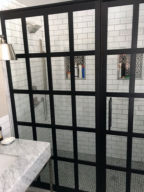 Black grid shower door with patterned cement tile floor