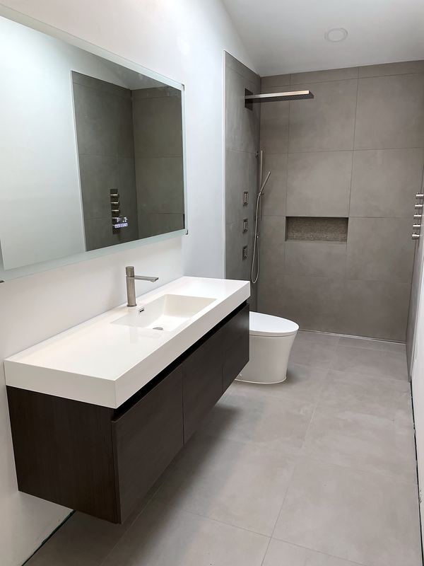 Floating vanity with integrated top and gray porcelain shower