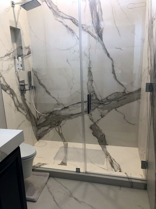 Frameless glass shower with bold marble-look slabs