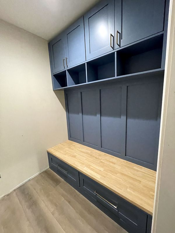 Custom mudroom bench with blue-gray cabinets and butcher block seat