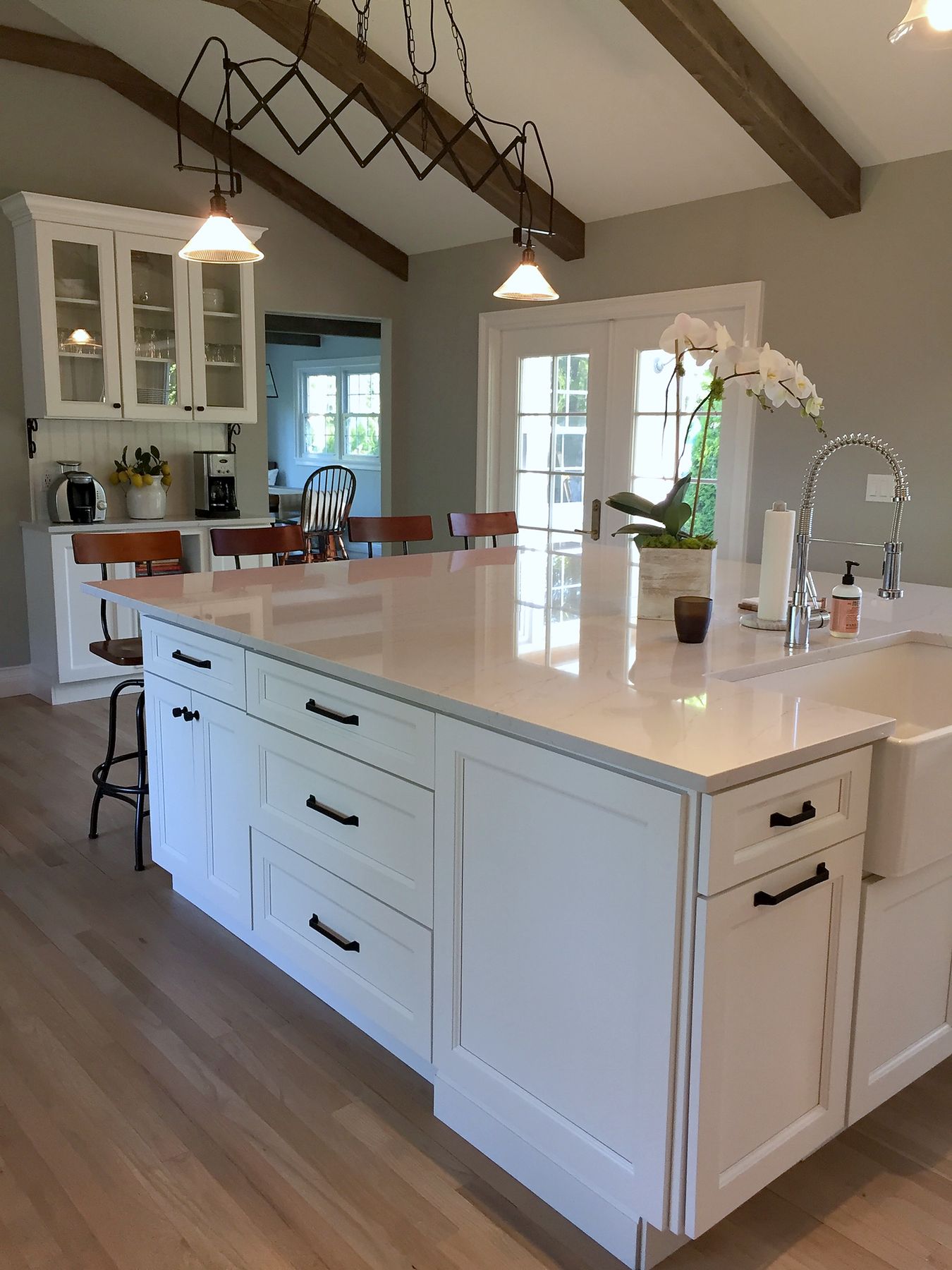 White kitchen remodel with large island, quartz top and vaulted beamed ceiling