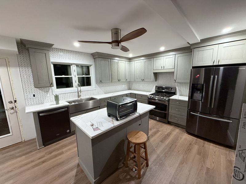 Gray shaker kitchen with island, wood floors and ceiling fan
